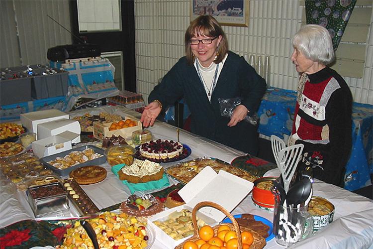 Margaret Rand gestures to a table filled with desserts as Marian Packham looks on.