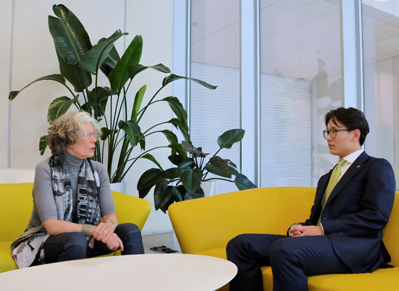 Two people sitting on bright yellow armchairs and having a conversation