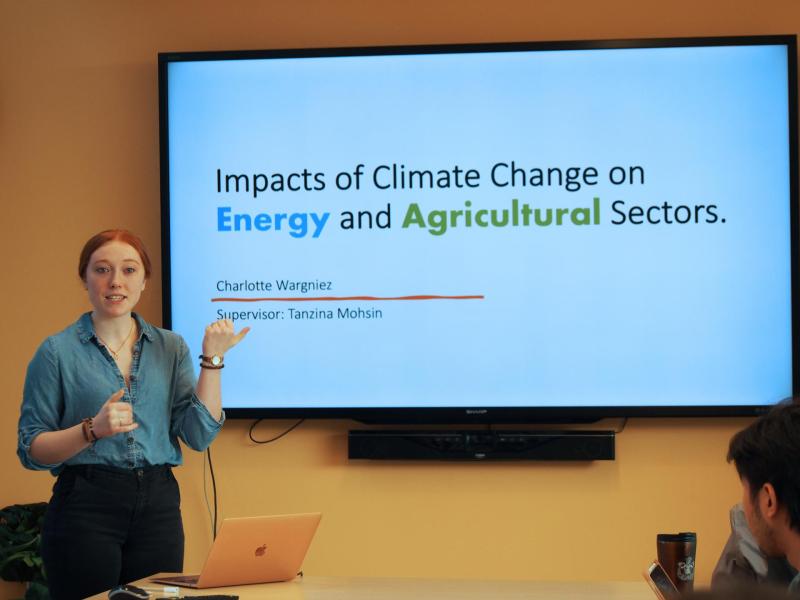 Charlotte stands in front of a large presentation screen