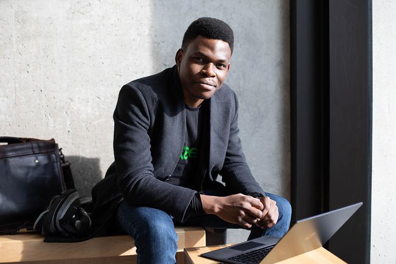 Olubenga Olubanjo smiles as he looks up from the laptop he is working on.