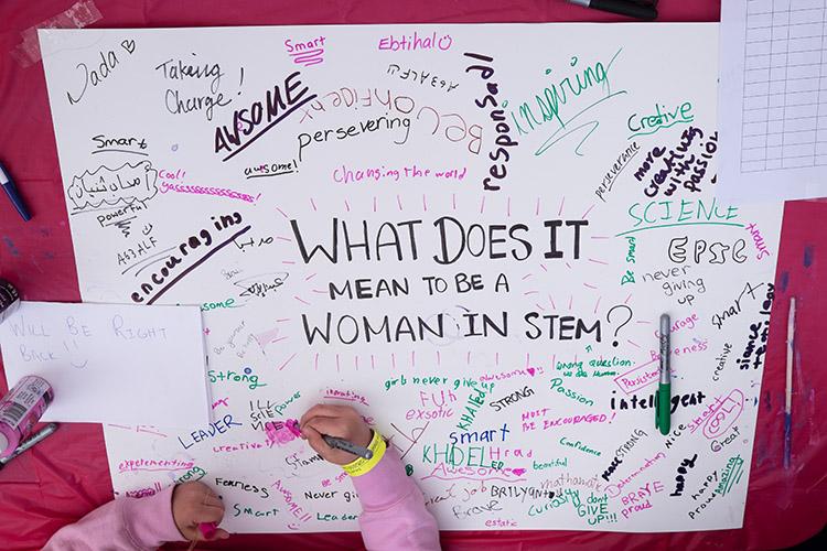 A girl adds to a poster about what it means to be a woman in science, technology, engineering and math (STEM) at Science Rendezvous on May 12 (photo by Geoffrey Vendeville).