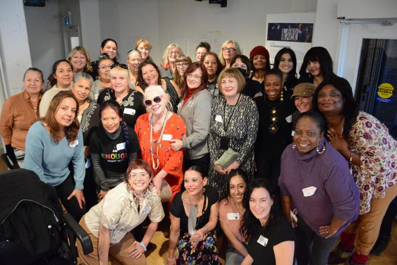 A large group of smiling women pose for a group shot, with Kaitlin Schwann at the front. 