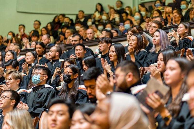 Rotman graduates smile and clap at Convocation Hall