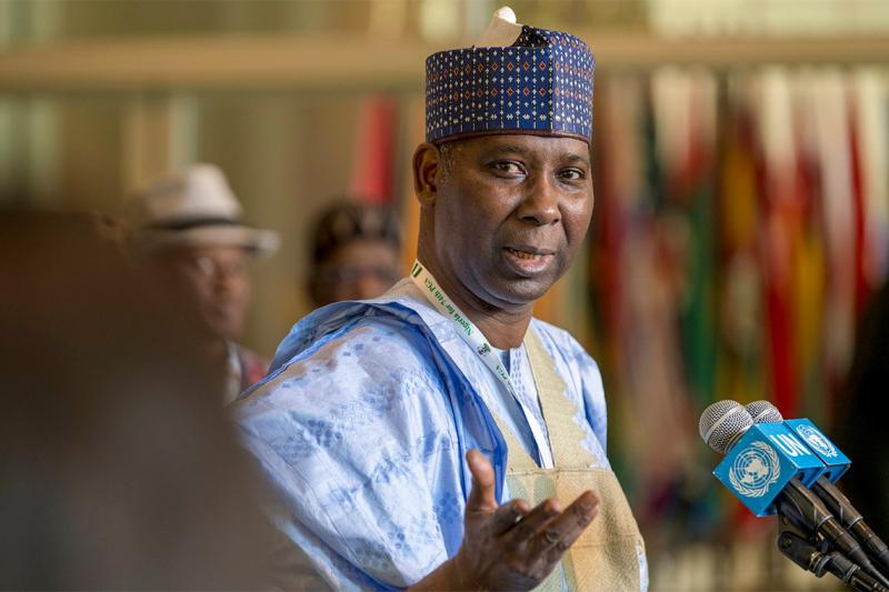 Tijjani Muhammad-Bande gestures as he stands at a microphone, wearing traditional Nigerian dress.