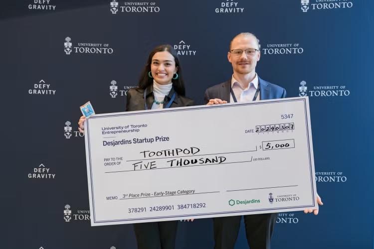 Two people holding a giant novelty cheque for $5000