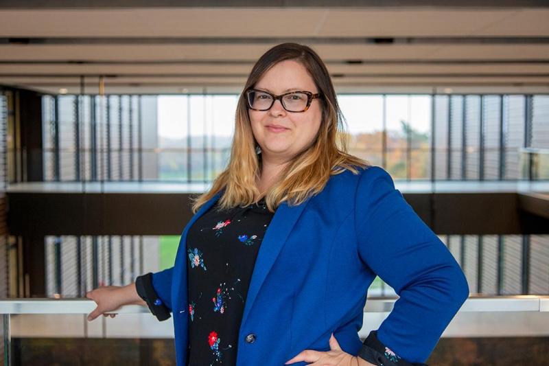 Jennifer Adese smiles while standing on a balcony at Maanjiwe nendamowinan, a U of T building with an Anishinaabemowin name.