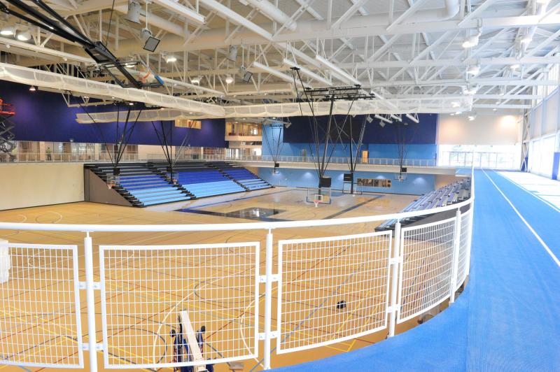 An indoor basketball court is circled by a raised balcony with an indoor running track on it.