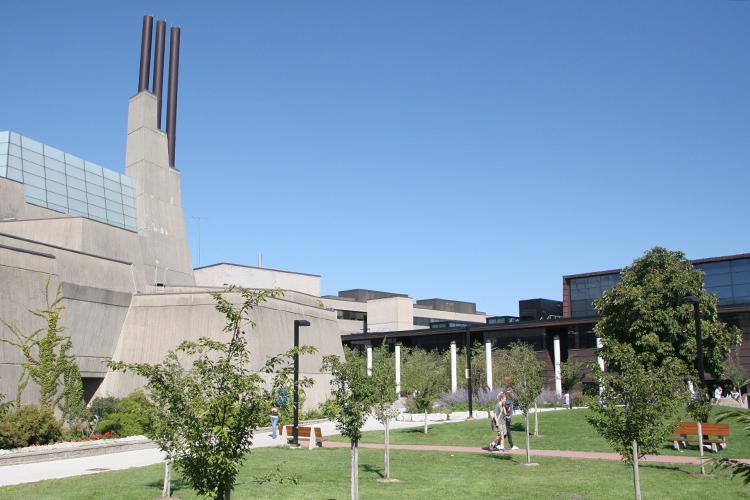 A green lawn leads up to a chunky concrete building with a tall tower shaped like three stairs.