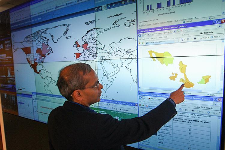 Vivek Goel points to a screen showing a map of Mexico. Different colours show rates of H1N1 flu cases in 2009.