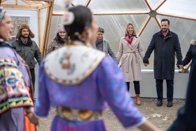 A group of people standing in a circle and holding hands inside one of the domes.