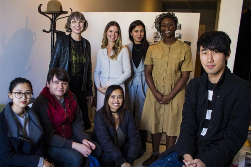 Ann MacDonald and Anique Jordan pose for a picture in an art gallery, with 6 students.