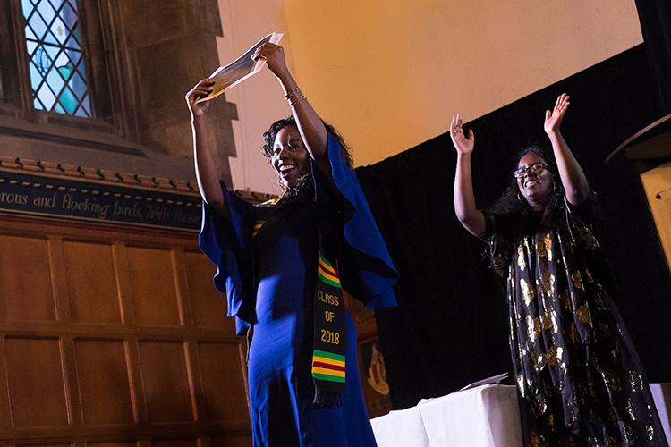 Dominic Stephenson, a health studies student at U of T Scarborough, holds her certificate up high as Black Grad organizer Ayaan Abudulle claps in the background.