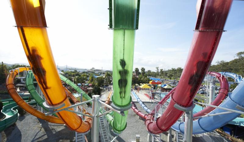 Several colourful water slides in a row photographed from the back.