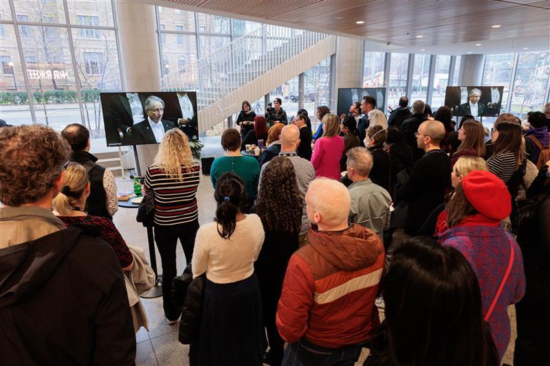 A group of people watching the Nobel Prize ceremony on a television