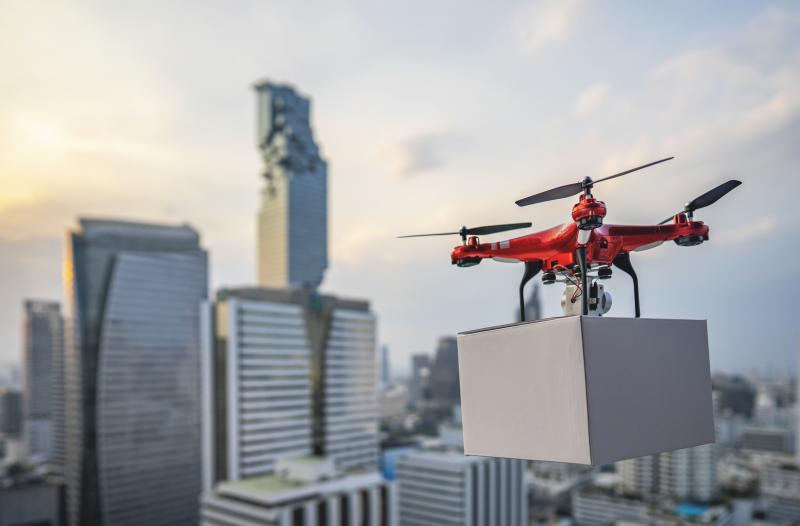 A drone carrying a box and flying over the city