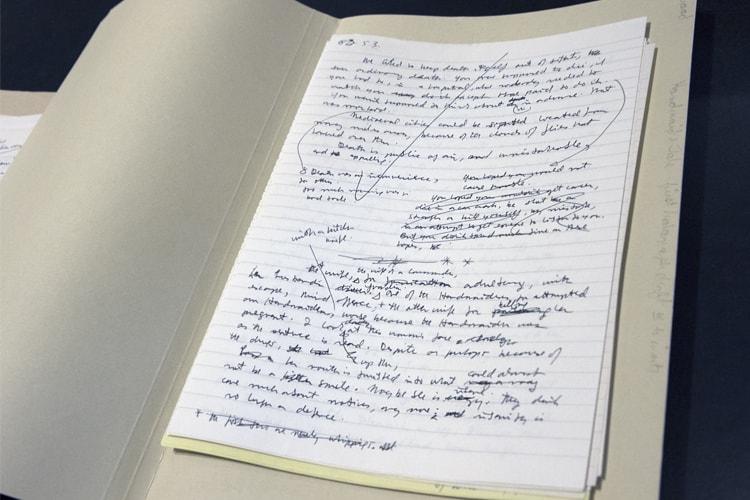 A handwritten page in a notebook features many crossed-out words and a giant checkmark.