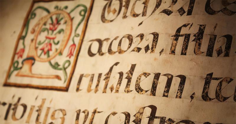 A page of a hand-written medieval manuscript shows ink writing, slightly faded, in old-fashioned letter shapes.