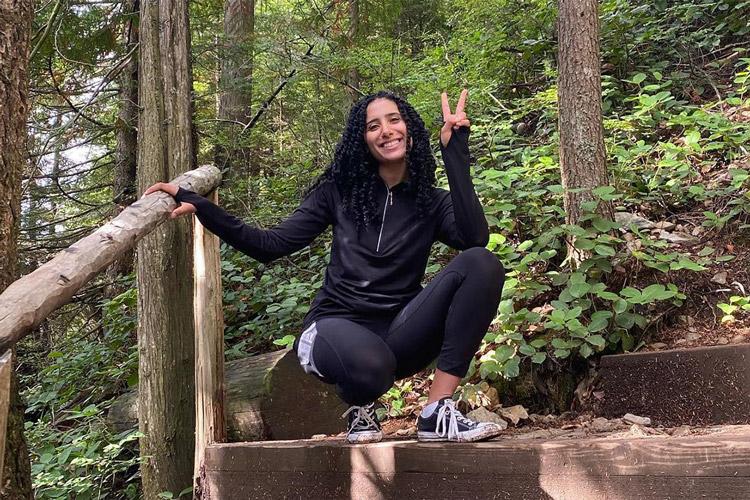 Iman Mounib makes a V for victory sign as she pauses on a staircase on a steep wooded hill.