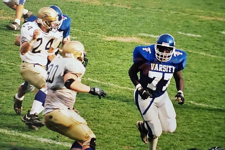 Wearing a Varsity Blues football uniform, Julius Lindsay is open for a pass while opposing players close in.