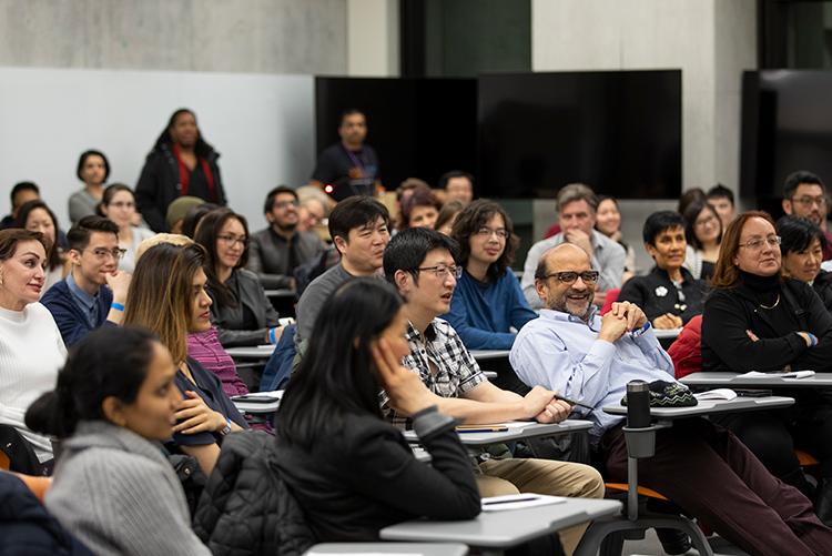 In a crowded audience listening to a talk, one man in the front row laughs out loud