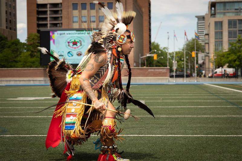 Matthew Rutledge dances in his ceremonial regalia on the turf at Varsity Stadium.