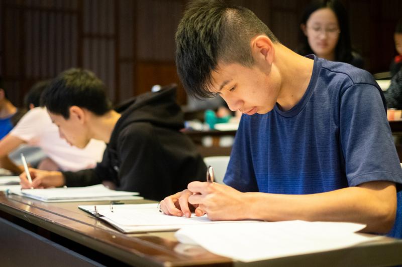 High school student Michael Liudeng bends over a worksheet with a look of intense concentration.