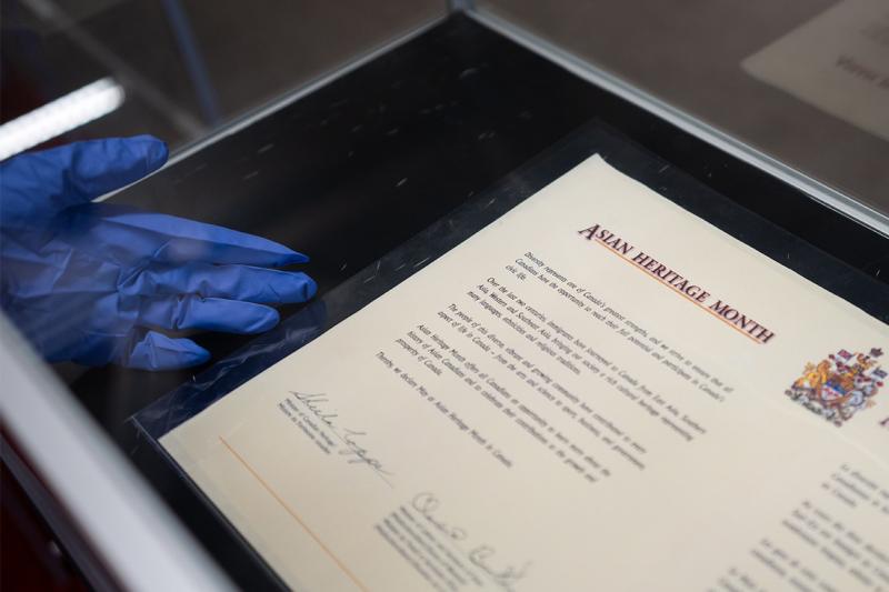 A formal certificate, with the headline Asian Heritage Month, displayed in a glass case.