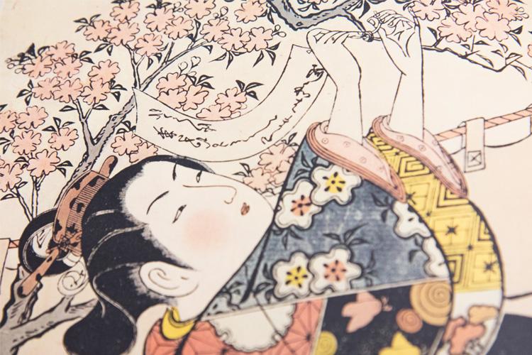 A stylized pen-and-ink-drawing of a Japanese woman tying a written paper to a blossoming tree branch.