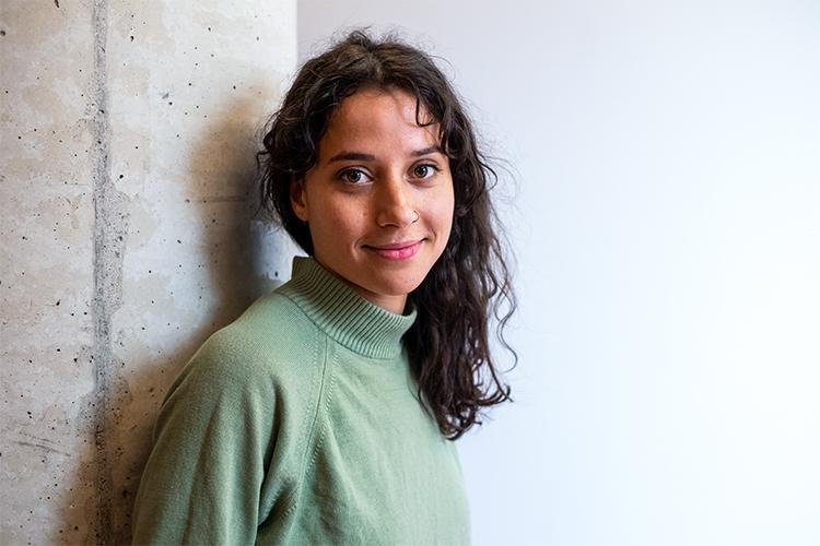 Rachel Giles smiles while leaning against a concrete pillar.