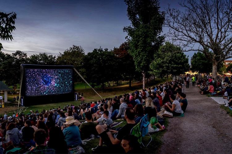 An audience in a park watching a movie outdoors