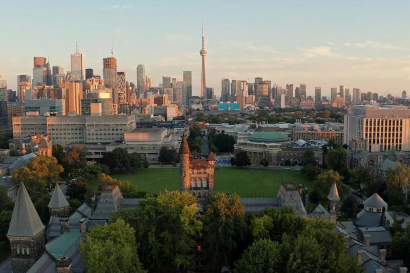 Front Campus and downtown Toronto stretch away into golden light, as seen from the top tower of University College at sunset.