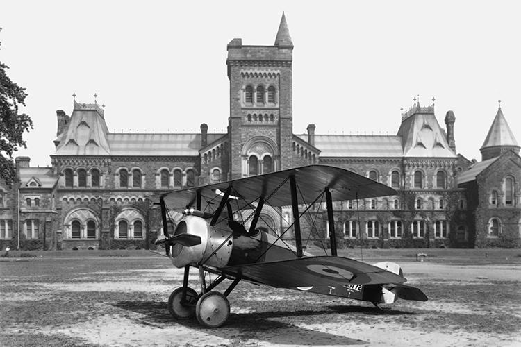 In a photograph from 1918, a small biplane with circles painted on its wings sits on U of T’s Front Campus.