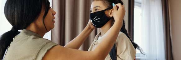 Caregiver helping child with mask