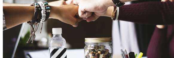 Several hands with varying skin tones fist-bump over a desk
