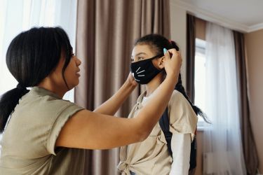 Caregiver helping child with mask