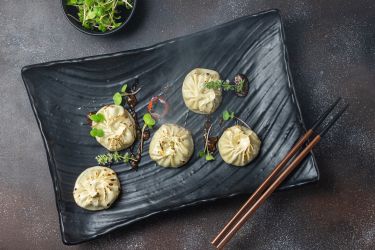 5 Dim Sum dumplings on a black rectangular dish