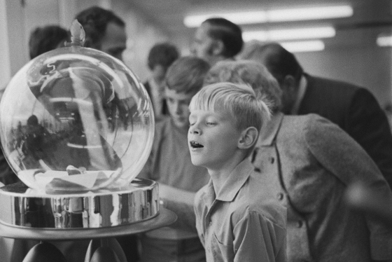A young boy stares open-mouthed at moon rocks displayed  under a glass bubble.