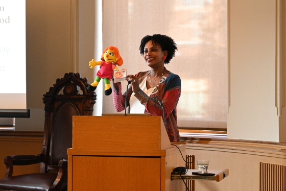 Rhonda McEwen stands at a podium with her puppet Julia