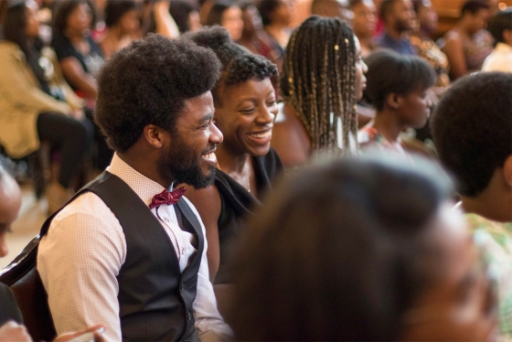 People laugh together as they sit in the audience for U of T's Black Graduation ceremony.