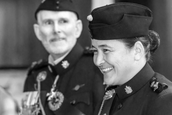 Vicky Sunohara smiles while wear a military hat and uniform with insignia on the collar.