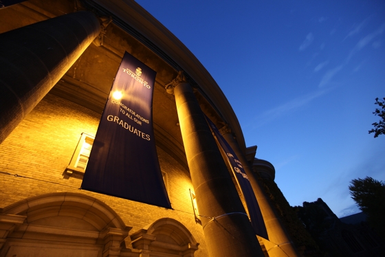 Convocation Hall glows at dusk. The banner reads: Congratulations to all our graduates.