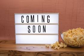 Bowl of popcorn sits next to sign saying coming soon