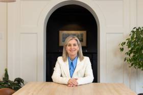 Melanie Woodin smiles while sitting behind a desk.