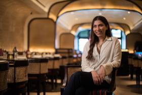 Ambica Jain sits in her restaurant Adrak Yorkville, smiling.
