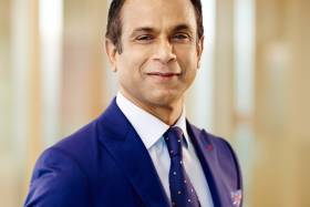 A portrait of Ramesh wearing a blue suit and tie