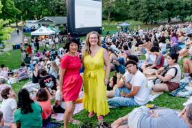 Emily Reid and Olivia Chow pose for a photo in front of an outdoor film audience