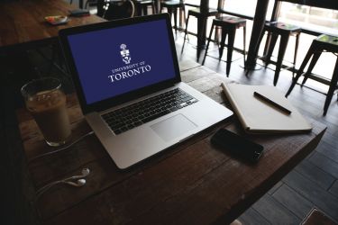 open laptop on a cafe table with the U of T logo on screen