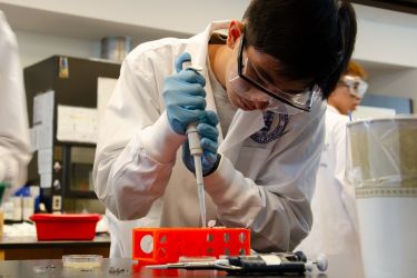 A high school student using a pipette in a science lab