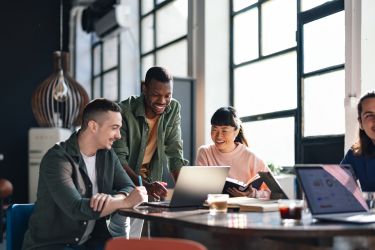 A group of people socializing and looking into a laptop 