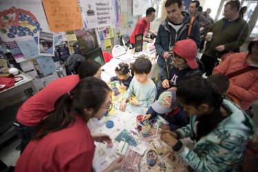 Image shows student volunteers and children doing science experiments.